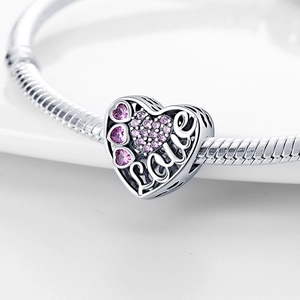 Macro shot of silver heart charm with pink crystals and Love engraving on snake chain