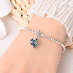 Detailed view of astronaut moon charm with luminous green stone on silver snake chain