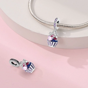 Macro detail of 925 silver cupcake charm with pink heart gemstone and enamel