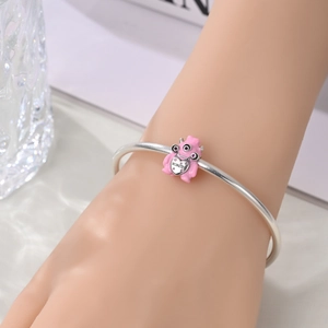 Silver open bangle with pink enamel monster charm featuring heart monster engraving