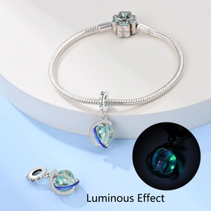 Detailed view of luminous astronaut planet charm and snake chain bracelet with floral clasp