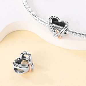 Zilveren hartbedel met I love you gravure en roségouden ring aan de slangenschakelarmband
