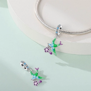 Detail of silver hummingbird charm with green enamel and purple flower on a snake chain