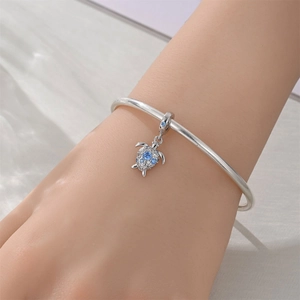 Silver bracelet with a sea turtle charm featuring blue and white zircon stones on a wrist
