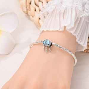 Dettaglio di un ciondolo a medusa in argento con smalto blu su bracciale a maglia snake