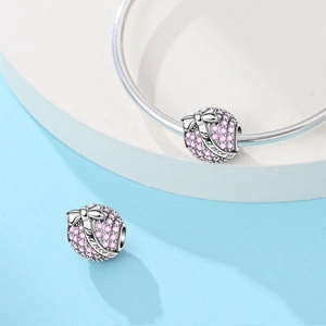 Close-up of a silver charm with pink gems and a bow engraved with Princess