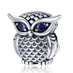 Détail d'une perle hibou en argent avec yeux en pierres bleues et textures de plumes
