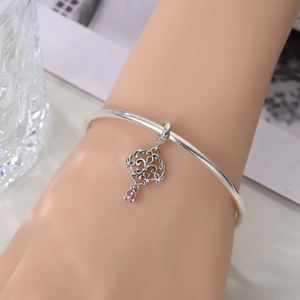 Close-up of silver-plated bracelet with hollow carving pink heart-shaped stone pendant