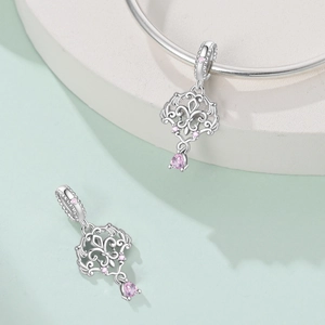Macro detail of silver baroque scroll charm with pink cubic zirconia on a bracelet