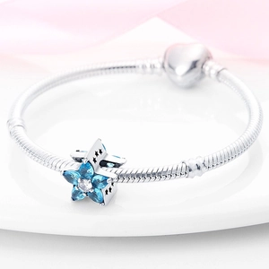 Silver snake chain bracelet with blue star charm and heart clasp on white tray