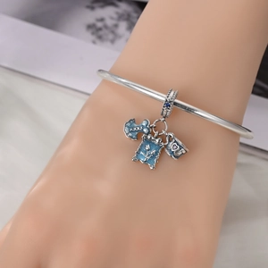 Silver bracelet with blue enamel tea cup and tulip charms worn on a woman's wrist