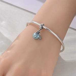 Detailed shot of silver bangle with blue heart moon charm and star pendant on wrist