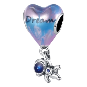 Macro detail of silver dream heart charm with gradient enamel and astronaut pendant