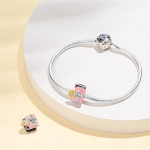 Detailed macro of silver snake chain bracelet with pink enamel and crystal flower charms