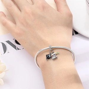 Silver charm bracelet with graduation cap and scroll pendant worn on a female wrist