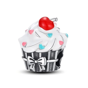 Macro shot of a silver cupcake charm with white enamel icing and tiny pink heart details