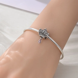 Detailed view of silver crown charm bracelet featuring purple teardrop gemstone pendant