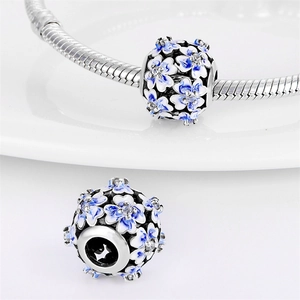 Détail macro du charm fleur en émail bleu avec oxydes de zirconium sur chaîne argent