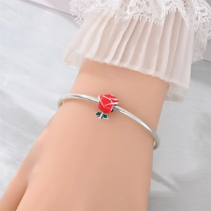 Detail of silver bracelet featuring a red rose flower charm on a lace sleeve wrist