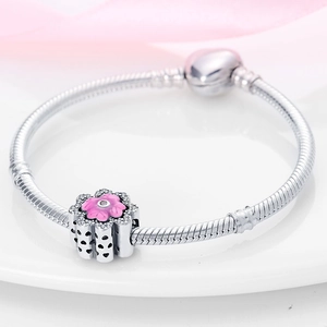 Detail of silver snake chain bracelet with pink enamel flower charm and heart cut-outs