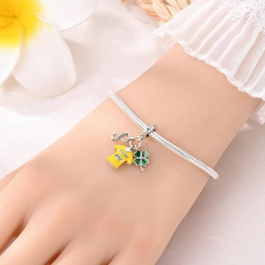 Detalle de pulsera de cadena de serpiente con dijes de fútbol amarillo y trébol