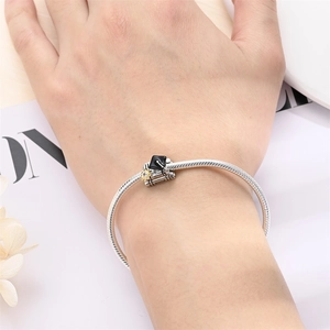 Detail of silver graduate bear charm with black cap and books on snake chain bracelet