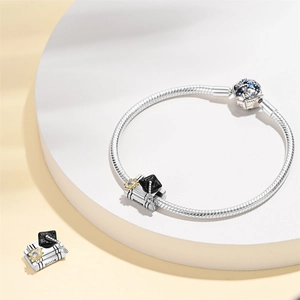 Detail view of graduation charm bracelet with silver snake chain and blue gemstone clasp
