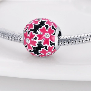 Detailed macro view of pink enamel flower charm with zircon inlays and silver plating