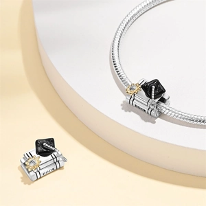 Detail of silver graduation charm featuring a cap, books, and sunflower on a snake chain