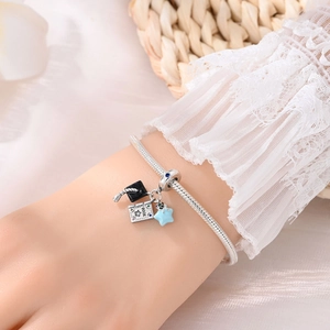 Silver snake chain bracelet featuring graduation bear and cap charms on a lace wrist