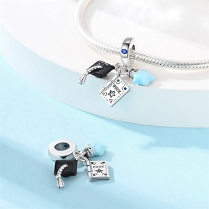 Macro shot of silver graduation charms featuring a black mortarboard and book on a bracelet