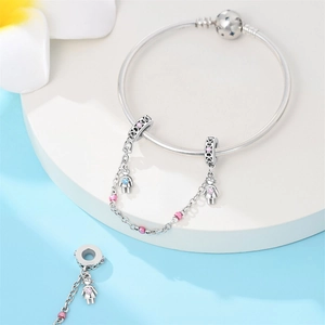 Silver bracelet detail showing girl and boy charms with pink and blue enamel accents