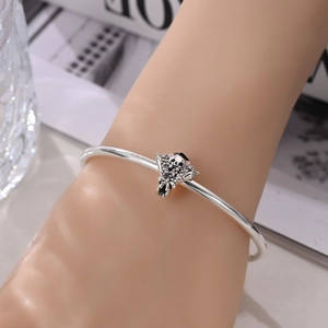 Detail of silver graduate panda bouquet charm on a sleek open cuff bracelet