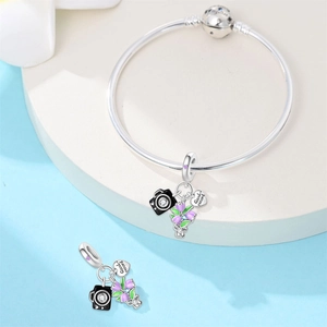 Detail of silver bangle with camera charm, purple flowers and Good Record heart tag
