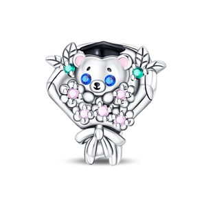 Macro shot of silver graduation bear charm with blue gem eyes and pink flowers