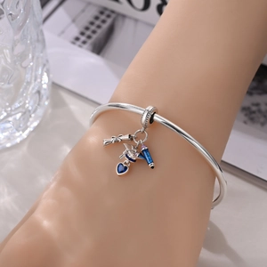 Silver graduation bracelet featuring a mortarboard, blue heart gem, and graduate charm