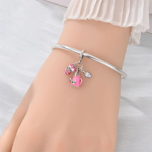 Silver open bangle with pink enamel gardening charms including a watering can and shovel