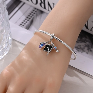 Silver graduation charm bracelet with black mortarboard cap and red ribbon scroll charms