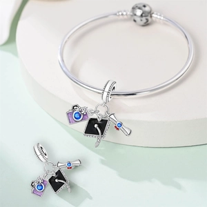Macro detail of silver graduation charms featuring a cap, diploma, and purple camera