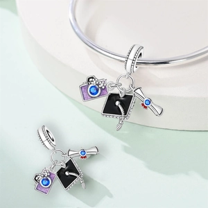 Macro detail of graduation charms with mortarboard and camera on a silver bracelet