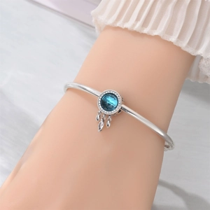 Detail view of silver dreamcatcher bangle with a blue stone and sparkling zircons