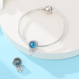 Detail of S925 silver dreamcatcher charm bracelet with blue gemstone on white pedestal