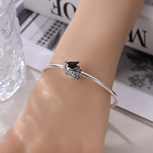 Detailed shot of silver graduation bracelet with black mortarboard and purple zircons