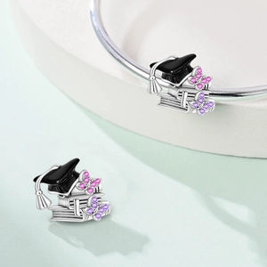 Macro detail of silver graduation charm featuring a black mortarboard and purple zircon