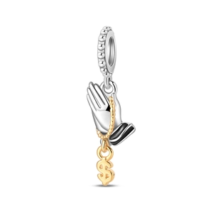 Macro detail of silver prayer hands charm with gold dollar sign for DIY jewelry