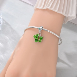 Detail of silver bracelet featuring green enamel dollar pendants and gemstone clasp