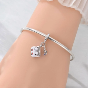 Detail of silver bangle with cherry suitcase and musical note charms on a model's wrist