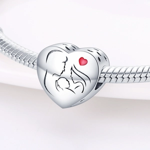 Primer plano de dije de corazón de plata con grabado familiar y corazón rojo en cadena
