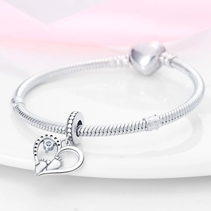 Detalle de pulsera de plata con cierre de corazón y colgante de huella de bebé