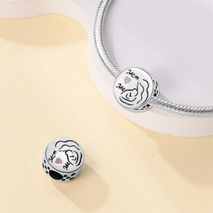 Detalle macro del charm de plata Mom and Me con corazón rosa y grabado madre-hijo